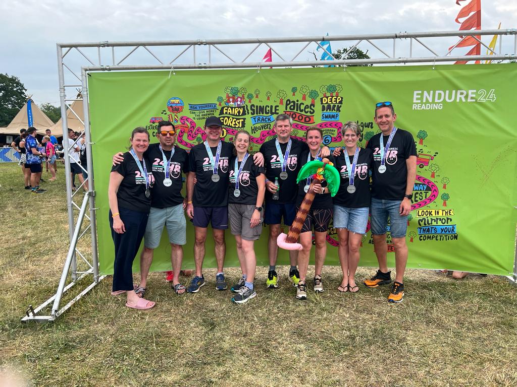 A group of runners in front of a green banner at the Endure 24 event