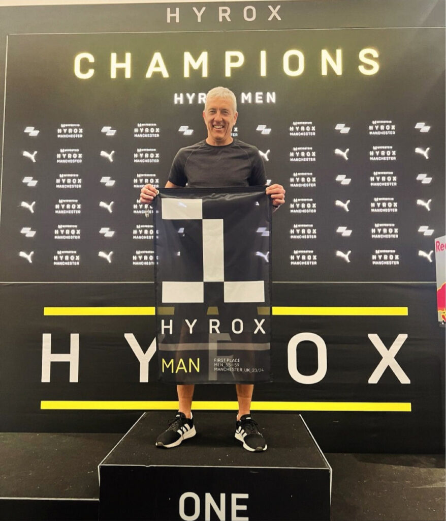 A man standing on a winners podium holding a banner
