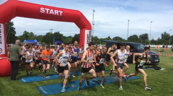 Runners underneath a starting arch and sprinting