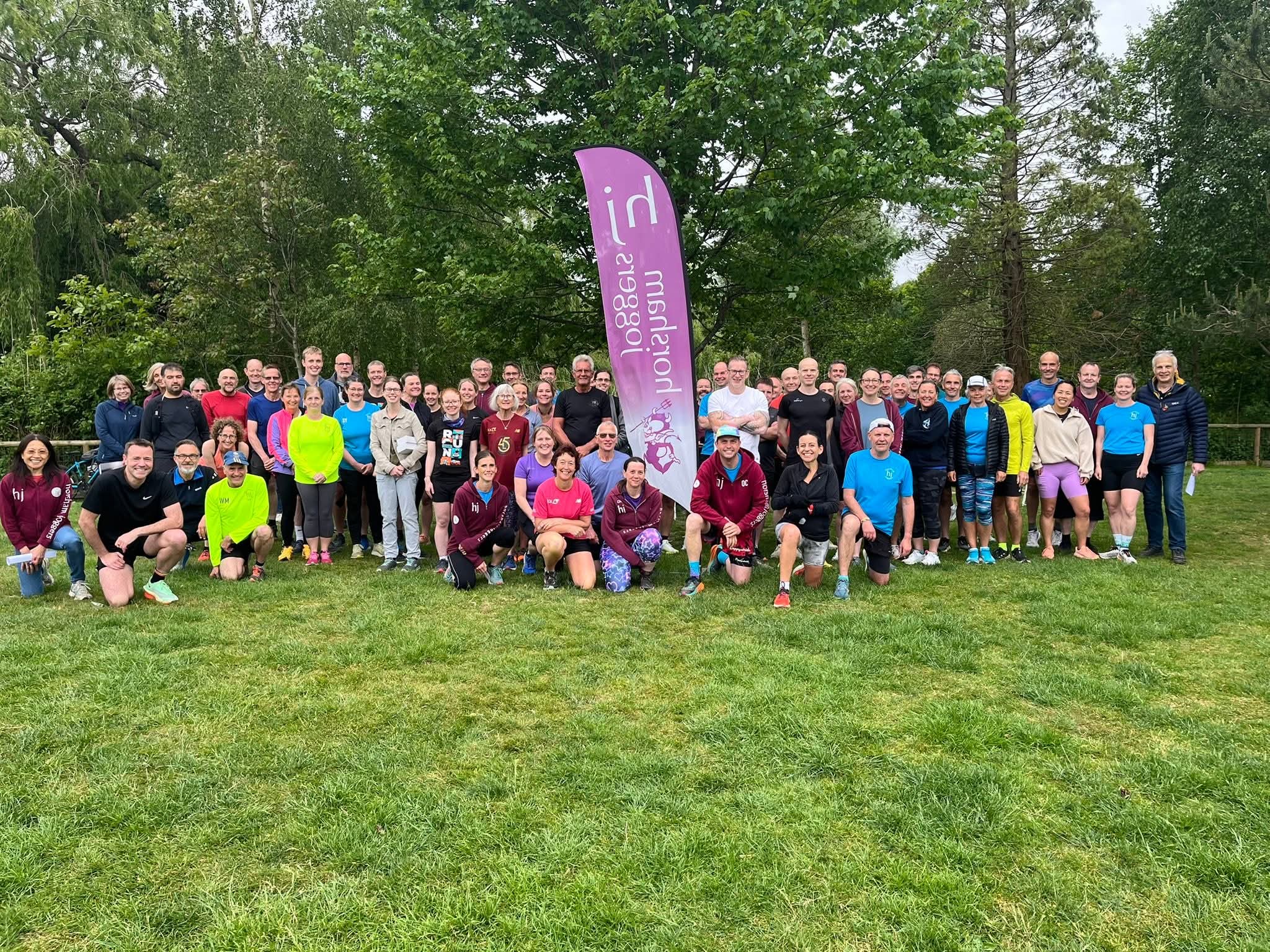 A large group of runners next to a club flag