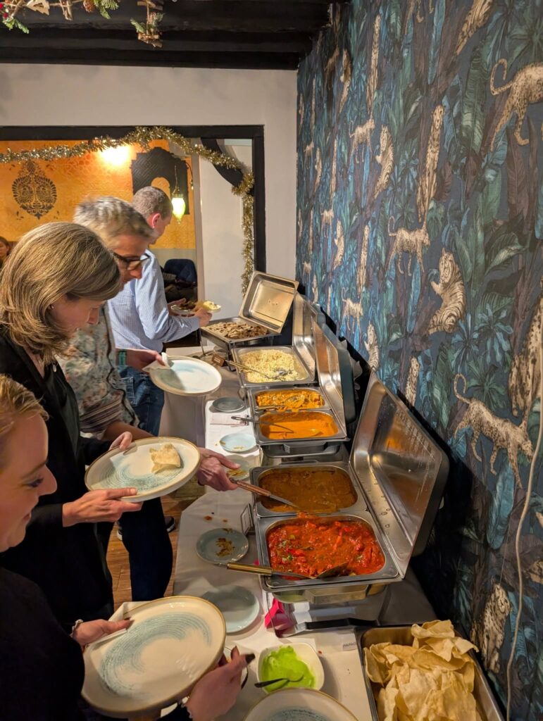 People choosing Indian food food at a buffet table