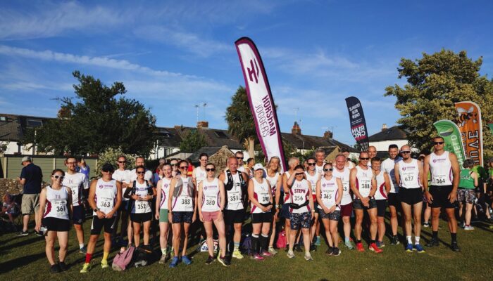 736367360_1446115674223524_5734026264432520875_n A large group of runners in front of a Horsham Joggers flag