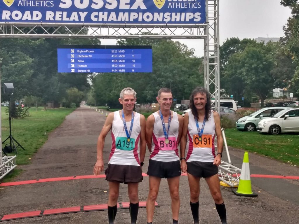 Three male runners under a finish arch
